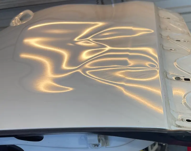 Hail-damaged panel under PDR inspection light showing dent pattern